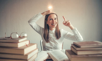 Eine Frau vor einem Stapel Bücher. Sie hebt den Zeigefinger und freut sich. Sie hat eine Lösung gefunden, die mit einer Glühbirne auf ihrem Kopf symbolisiert wird.